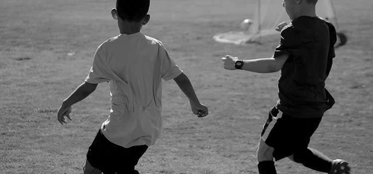 Svartvit bild med två barn som spelar fotboll på en grusplan