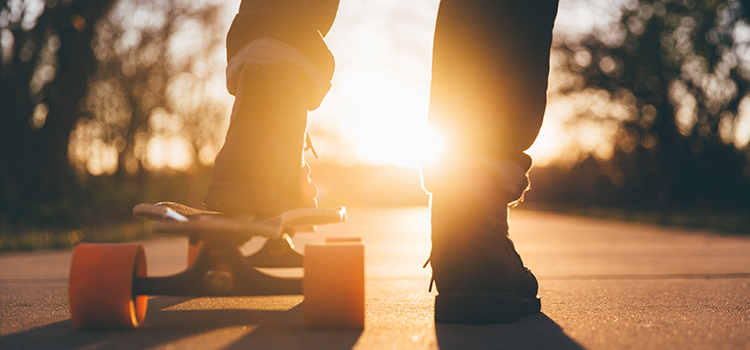 En sko klädd fot på en skateboard i solnedgång