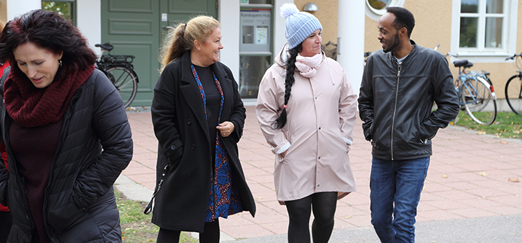 Tre kvinnor och en man går utomhus i höst- och vinterkläder.