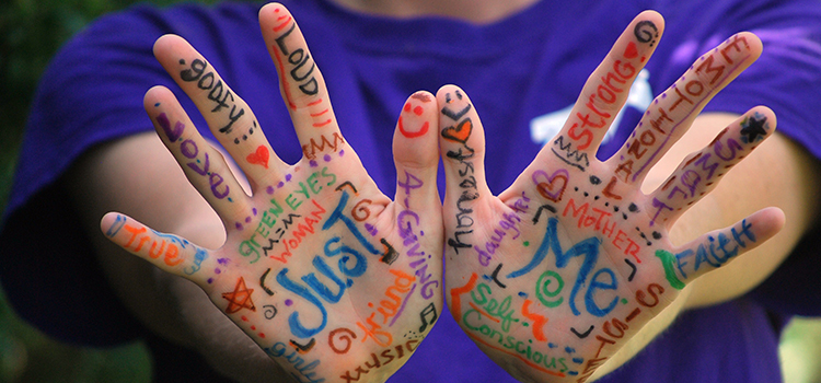 Två händer i fokus med olika ord på engelska skrivet i handflatorna och upp på fingrarna.