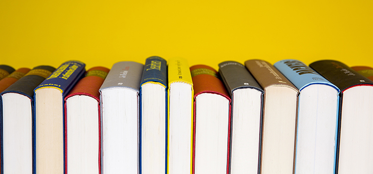 En bild med böcker i en lång rad med en gul bakgrund.