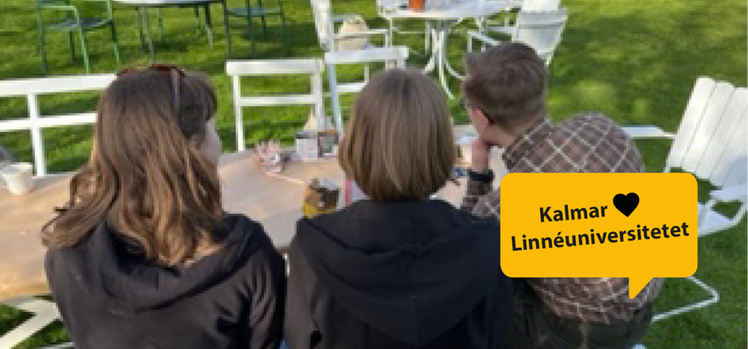 Tre studenter sitter med ryggen mot kameran vid ett cafébord i Krusenstiernska trädgården.